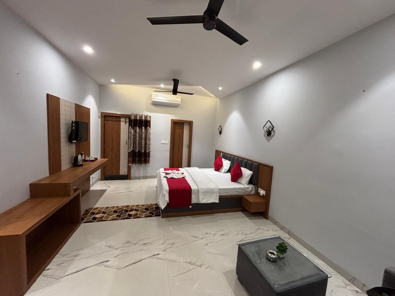 Une chambre moderne avec un lit, des tables de chevet, un bureau et un ventilateur de plafond.
