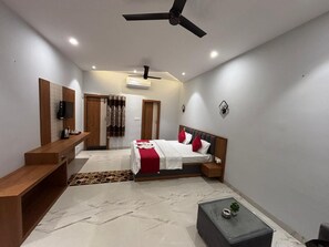 A modern bedroom with a bed, bedside tables, a desk, and a ceiling fan.