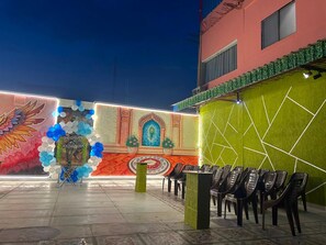 An outdoor seating area with chairs and a decorative wall featuring a mural and geometric patterns.