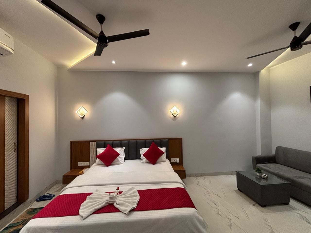 Une chambre moderne avec un lit, des tables de chevet, un canapé et des ventilateurs de plafond.