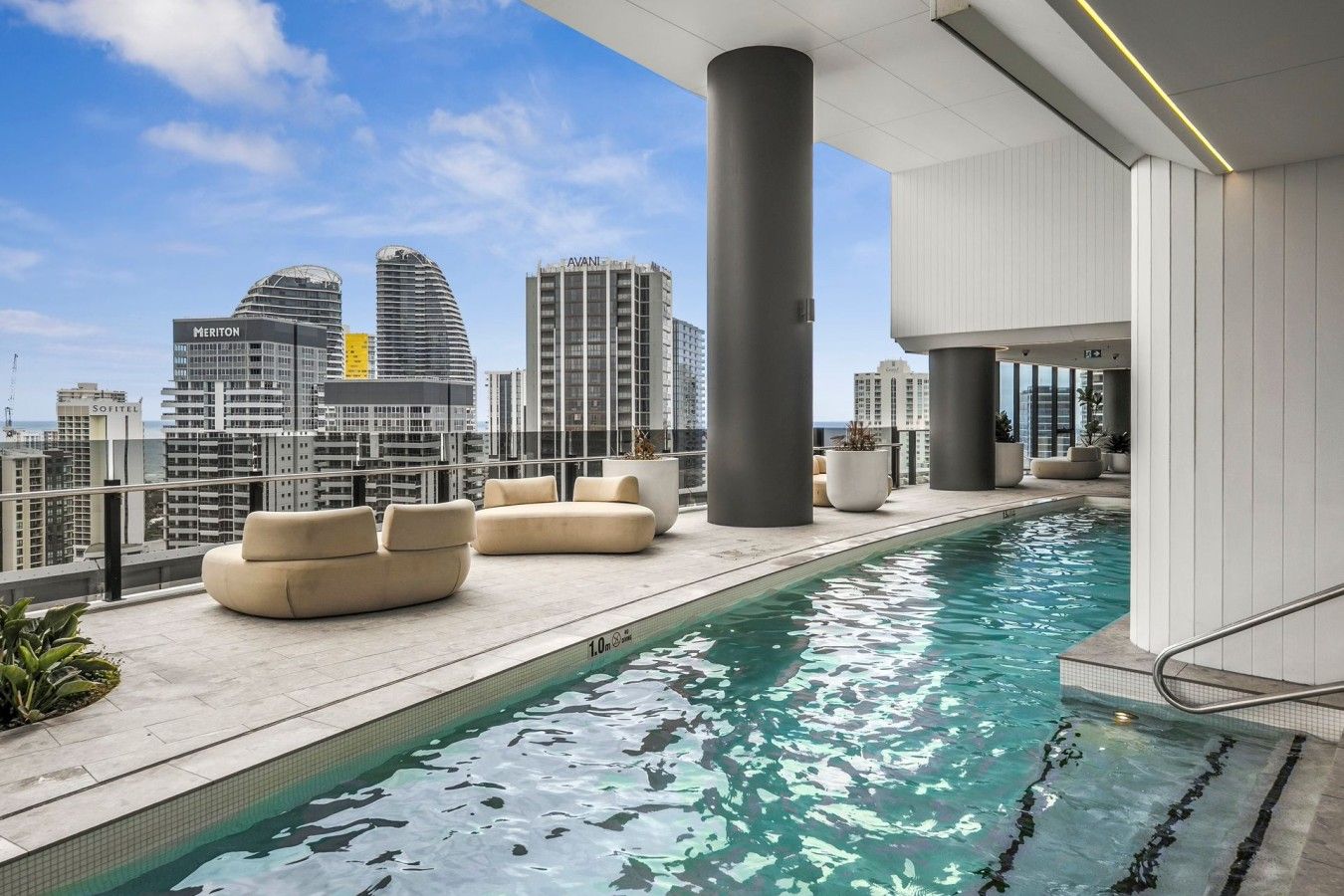 A rooftop pool area with seating and a city skyline view.