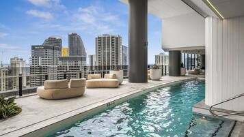 A rooftop pool area with seating and a city skyline view.