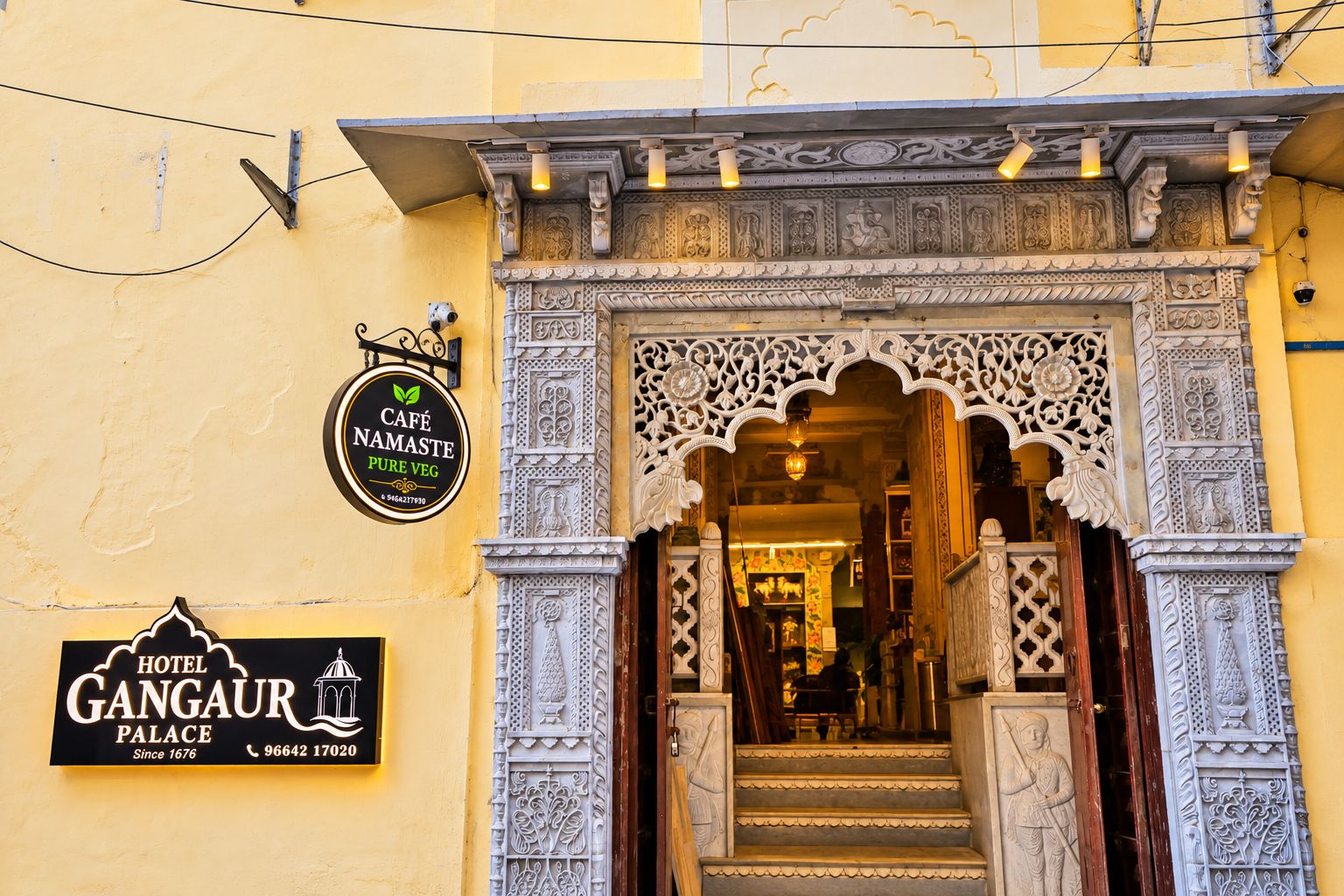 A hotel entrance with ornate carvings and a sign for Café Namaste Pure Veg.