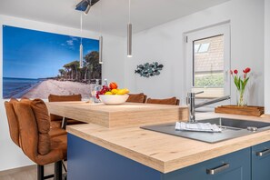 Eine moderne Küche mit einer Holztischinsel, einer eingebauten Spüle und Blick auf den Strand.