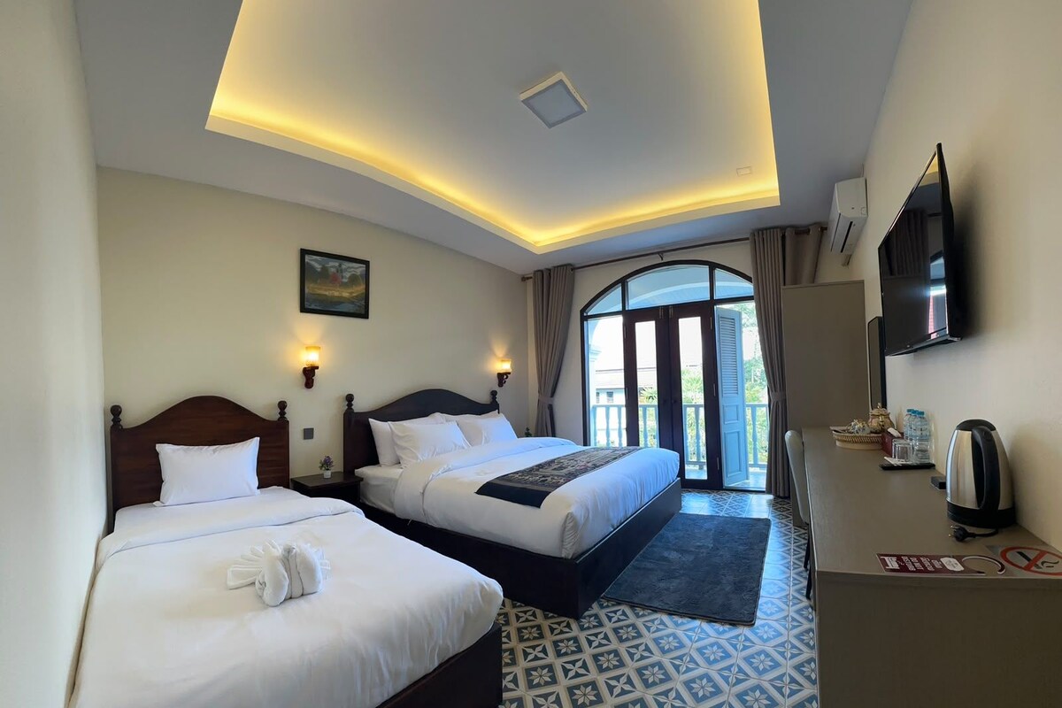Habitación de hotel con dos camas, televisión y vistas al exterior.