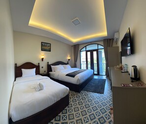 Habitación de hotel con dos camas, televisión y vistas al exterior.