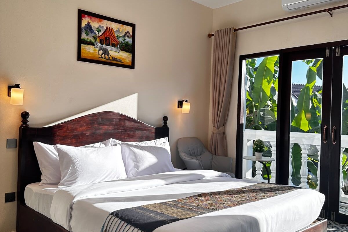 Habitación de hotel con una cama grande, un cuadro en la pared, una silla y vistas a zonas verdes a través de la ventana.