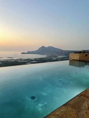 Une piscine à débordement offrant une vue dégagée sur la mer et les montagnes lointaines.