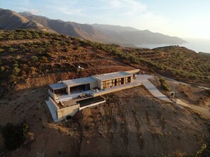 Une maison moderne avec un toit plat, de grandes fenêtres et une piscine.