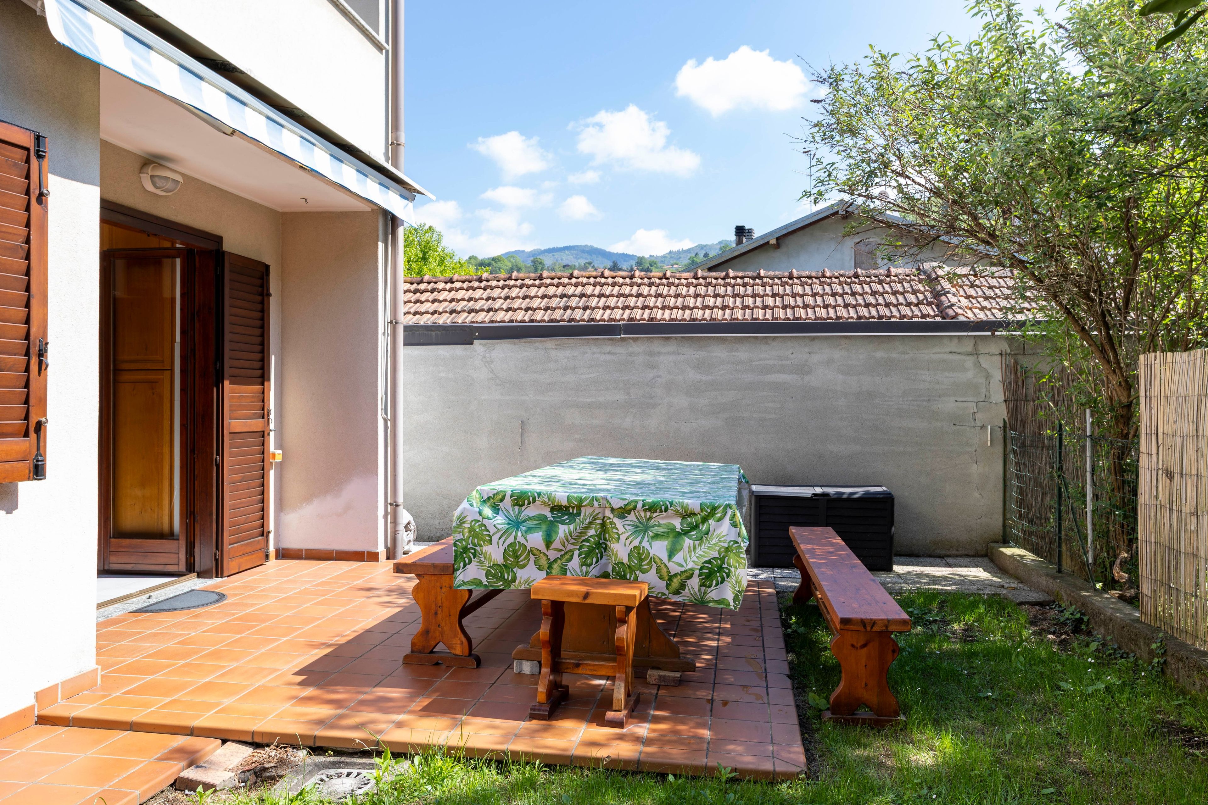 A patio with a table and benches, a covered area, and a view of a mountain range.