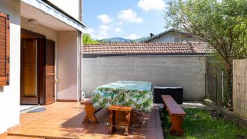 A patio with a table and benches, a covered area, and a view of a mountain range.