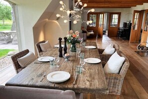 A dining area with a wooden table set for four, surrounded by wicker chairs with cushions.