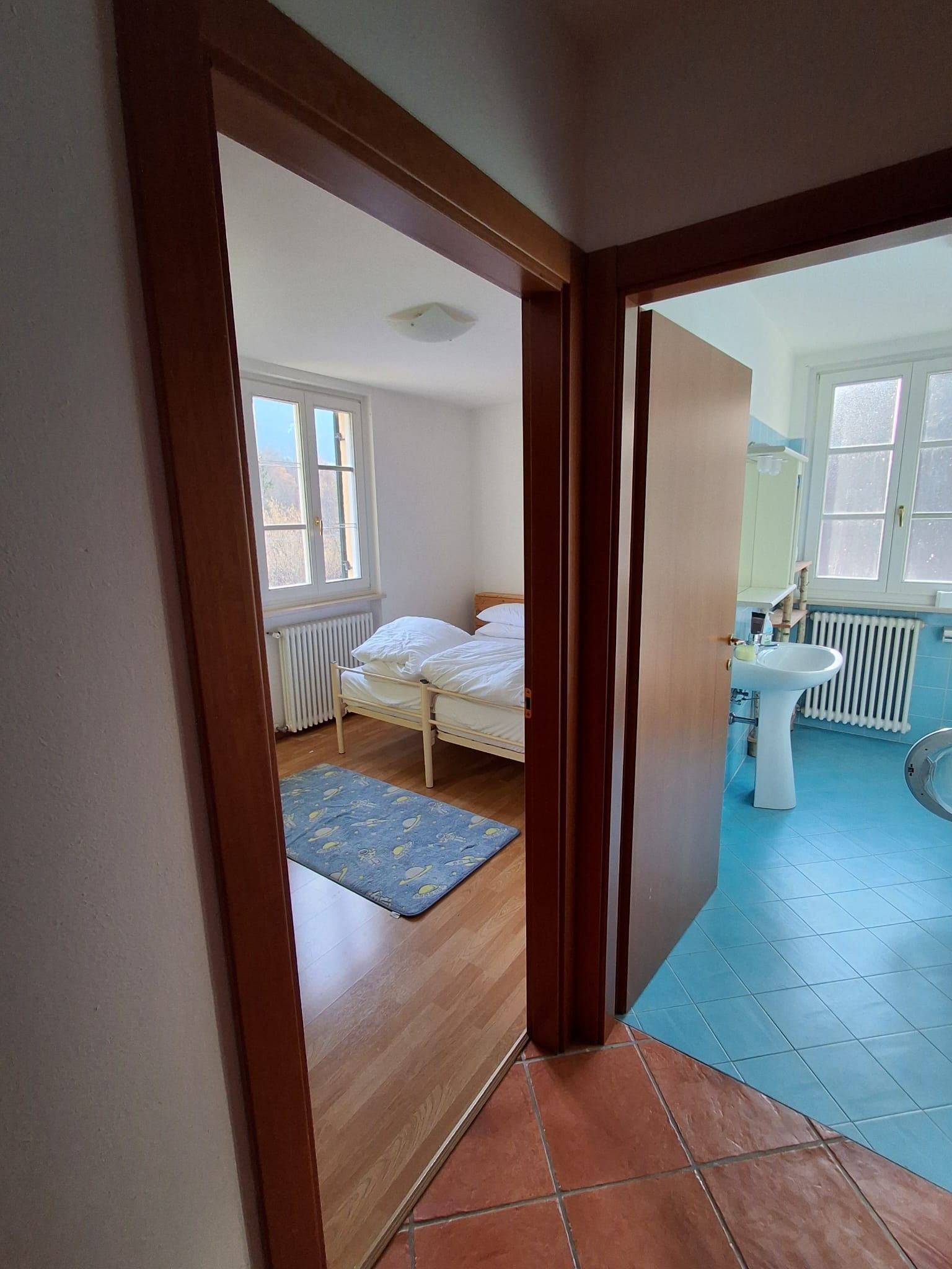A bedroom with a bed, a radiator, and a window.