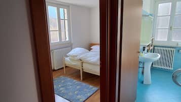 A bedroom with a bed, a radiator, and a window.