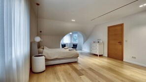 Une chambre à coucher avec un lit, une commode, une chaise et une grande fenêtre.