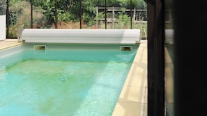 Une piscine dotée d’une terrasse en bois et offrant une vue sur la verdure en arrière-plan.