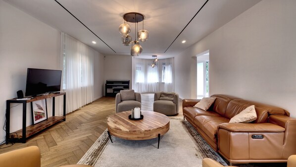 Un salon moderne avec un téléviseur à écran plat, un canapé en cuir et une table basse en bois.