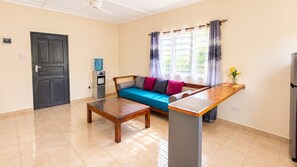 Sala de estar con sofá, mesa de centro, dispensador de agua y refrigerador.