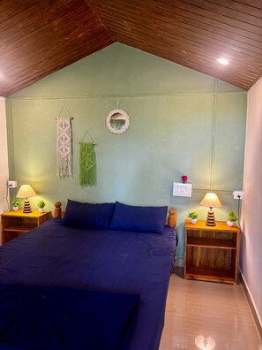 Een slaapkamer met een bed, twee nachtkastjes met lampen, een spiegel aan de muur en macramé decoraties.