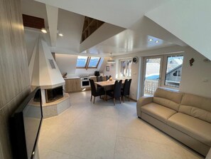 Ein modernes Interieur mit Essbereich, einer Couch und einem Kamin.