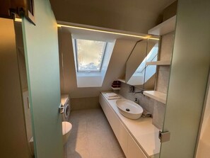 Ein modernes Badezimmer mit Oberlicht, integriertem Waschbecken und Toilette.