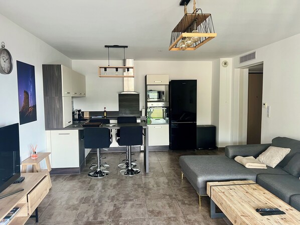 Een moderne keuken met een eethoek, een grijze bank en een houten salontafel.