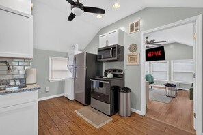 Une cuisine moderne équipée d’un réfrigérateur, d’un four à micro-ondes, d’une cuisinière et d’un ventilateur de plafond.