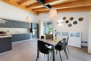 Eine moderne Küche mit grauen Schränken, einer Holzbalkendecke und einem Essbereich mit Tisch und Stühlen.