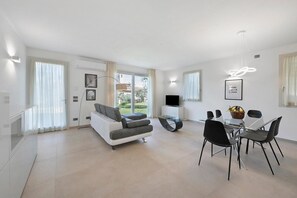 Ein modernes Wohnzimmer mit einer Couch, einem Esstisch mit Stühlen und einem Fernseher.