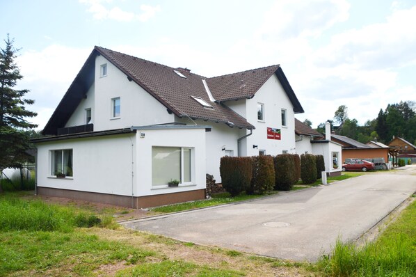 Ein zweistöckiges Wohnhaus mit geneigtem Dach, einer kleinen angebauten Garage und einer sichtbaren Hausnummer.