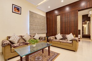 A modern living room with two sofas, a glass coffee table, and a patterned rug. - Townhouse Sankat Mochan Hanuman Temple (Varanasi)