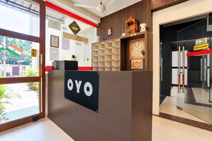 A reception desk with a sign that reads 'OYO' and a glass door leading to a restaurant. - Townhouse Sankat Mochan Hanuman Temple (Varanasi)