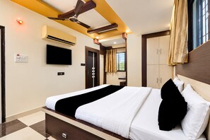 Habitació d'hotel amb llit, ventilador de sostre, aire condicionat, televisió i armari.