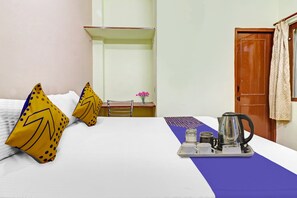A hotel room with a bed, pillows, a table with a tray, a kettle, and a door. - Hotel O Prem Nagar Dehradun (Dehradun)