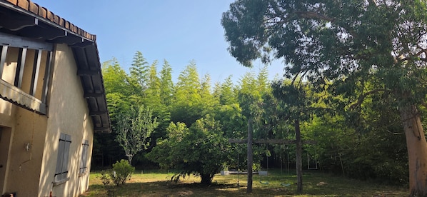 Un bâtiment doté d’un toit en pente et d’un jardin agrémenté d’arbres et d’une balançoire.
