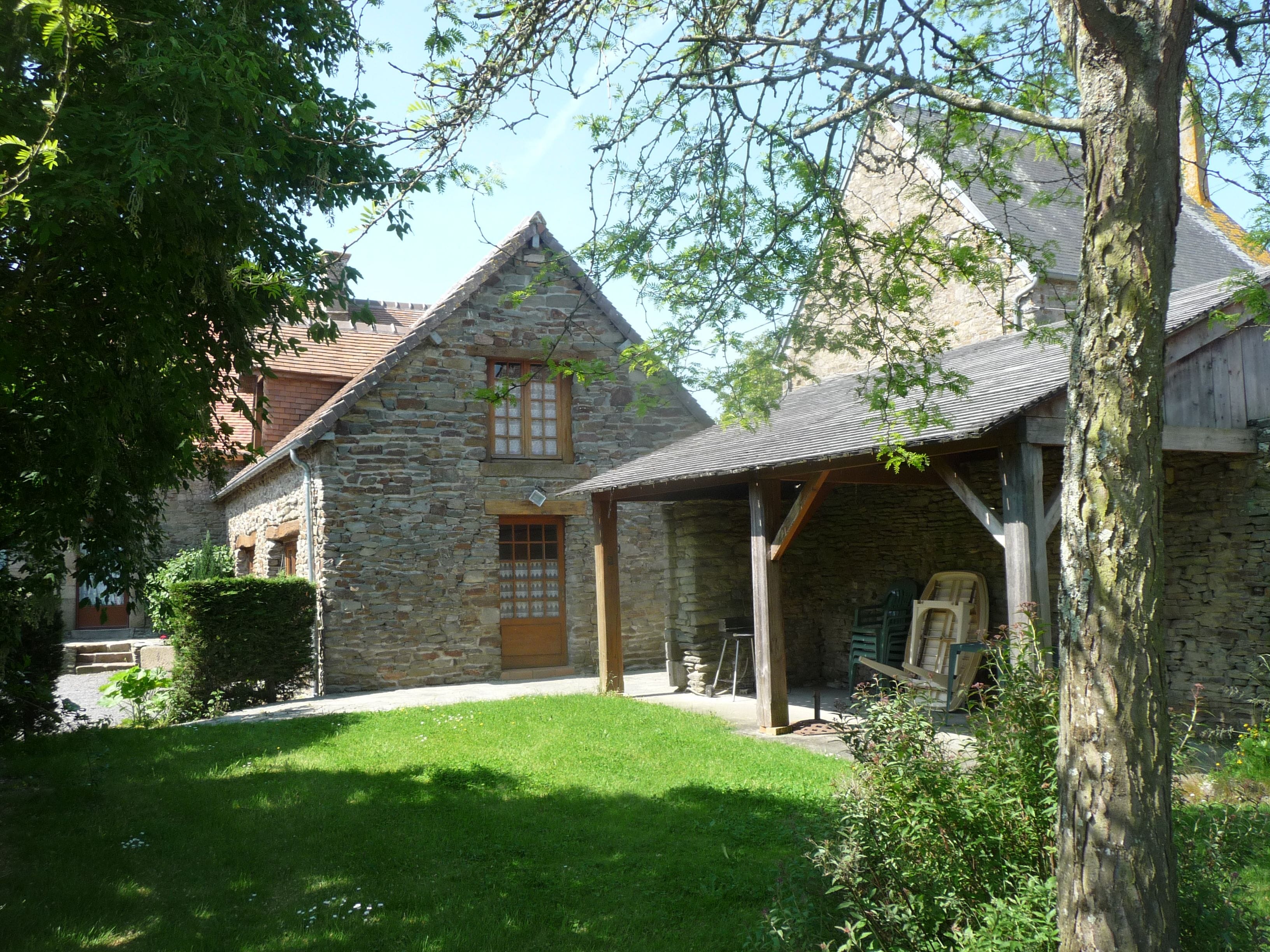 Ein Gebäude aus Stein mit einem geneigten Dach, einer Holztür und einer kleinen Veranda.