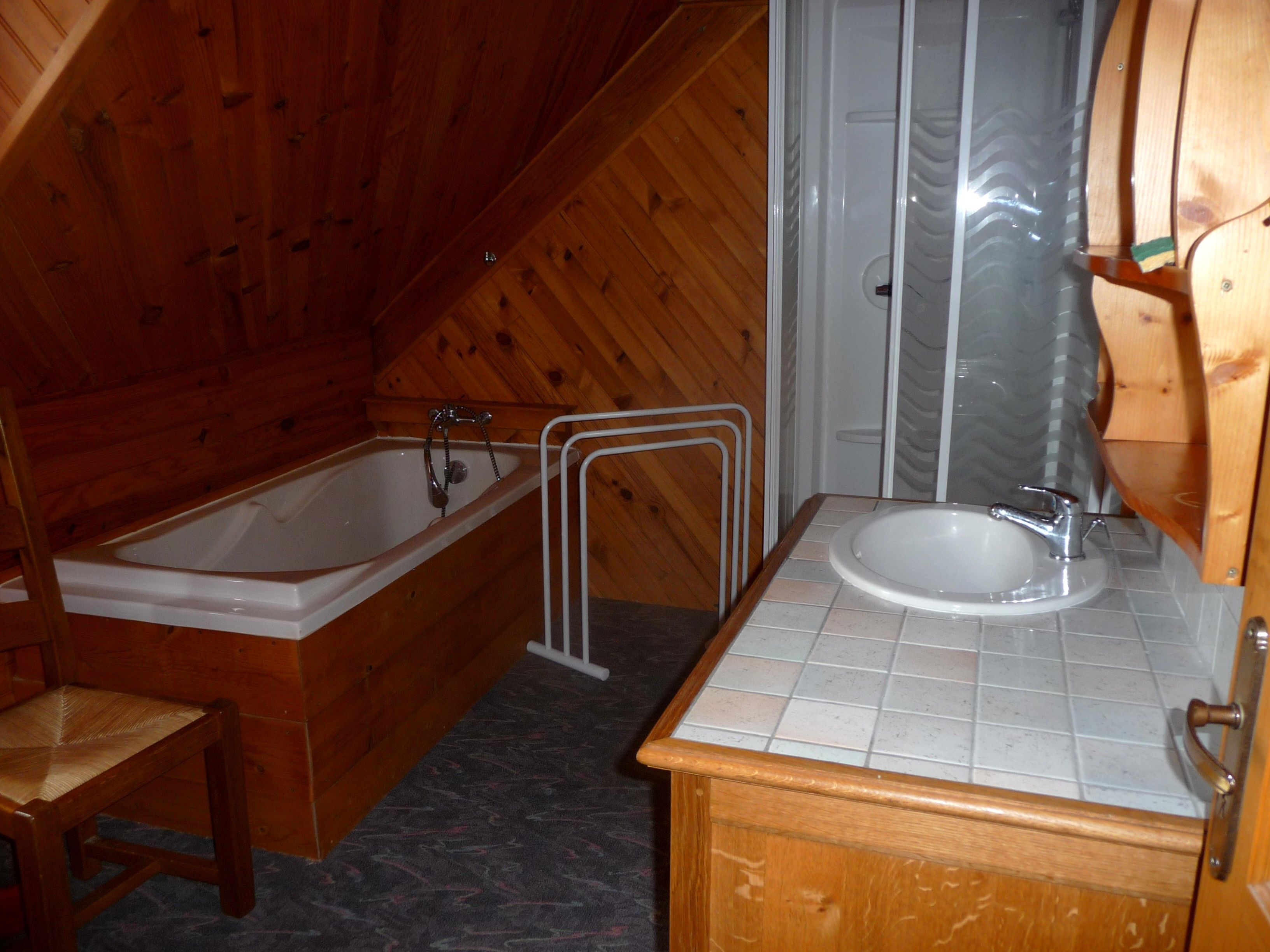 Ein Badezimmer einer Holzhütte mit Badewanne, Waschbecken und Dusche.