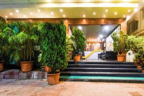 Een hotelentree met een trap die naar de lobby leidt, omringd door potplanten.