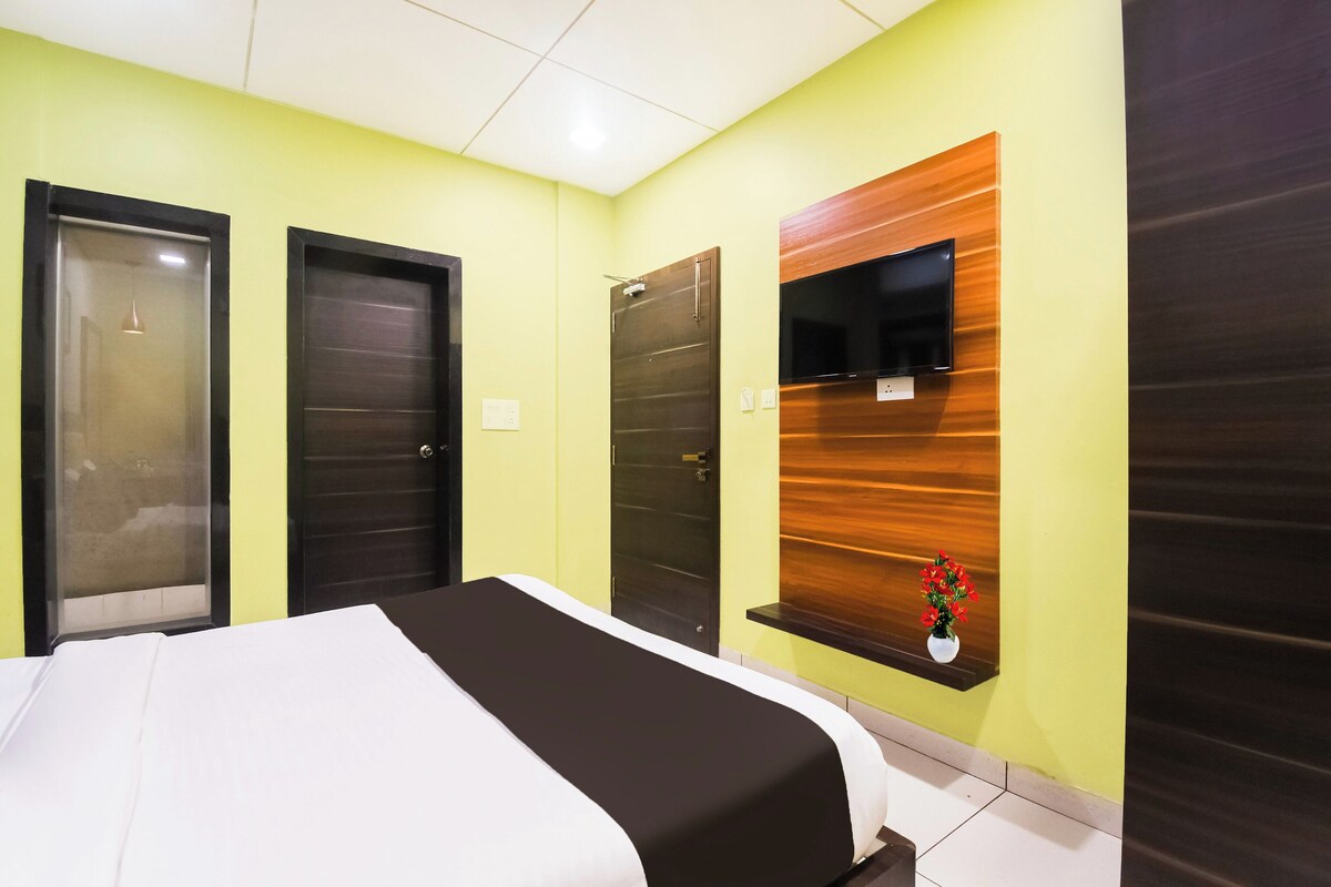 Een hotelkamer met een bed, twee deuren, een wand van houten panelen en een klein plankje met een bloem.