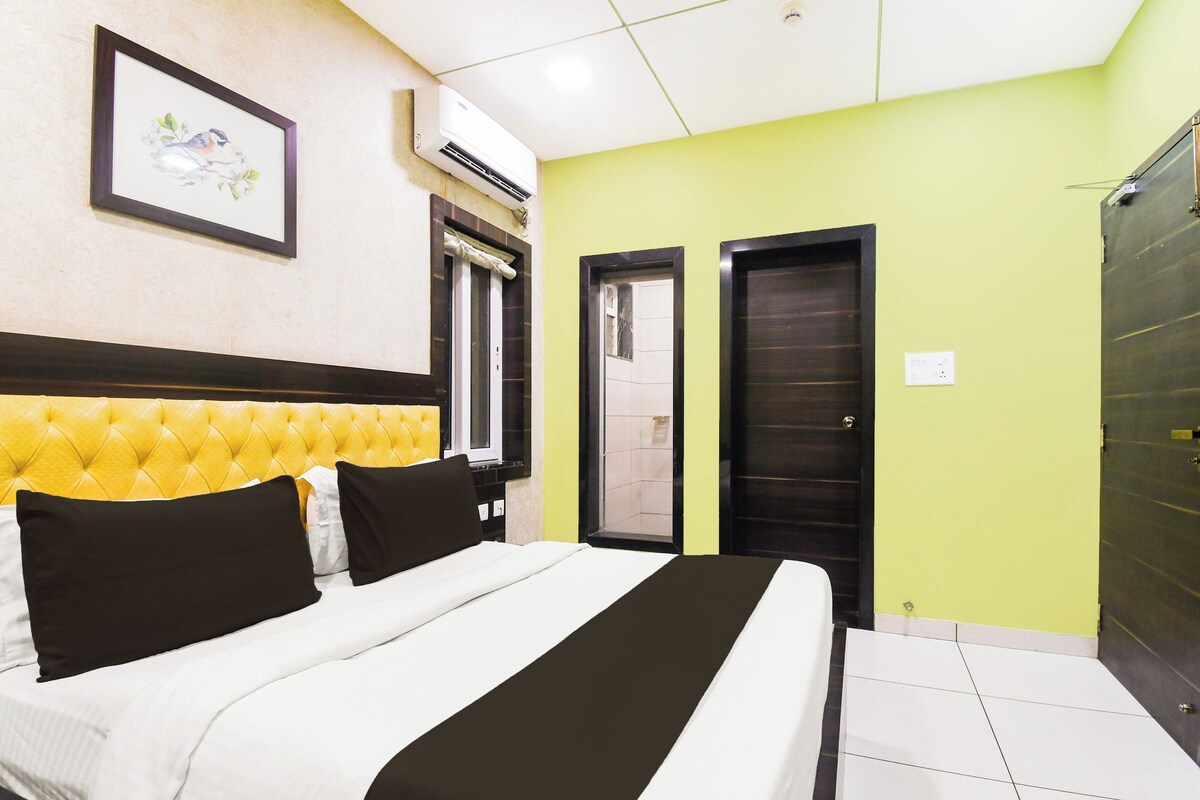 Een hotelkamer met een bed, een ingelijst schilderij aan de muur, een airconditioning en twee deuren.
