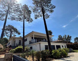 Un bâtiment à deux étages doté d’un balcon au niveau supérieur, entouré d’arbres et surplombant un ciel dégagé.