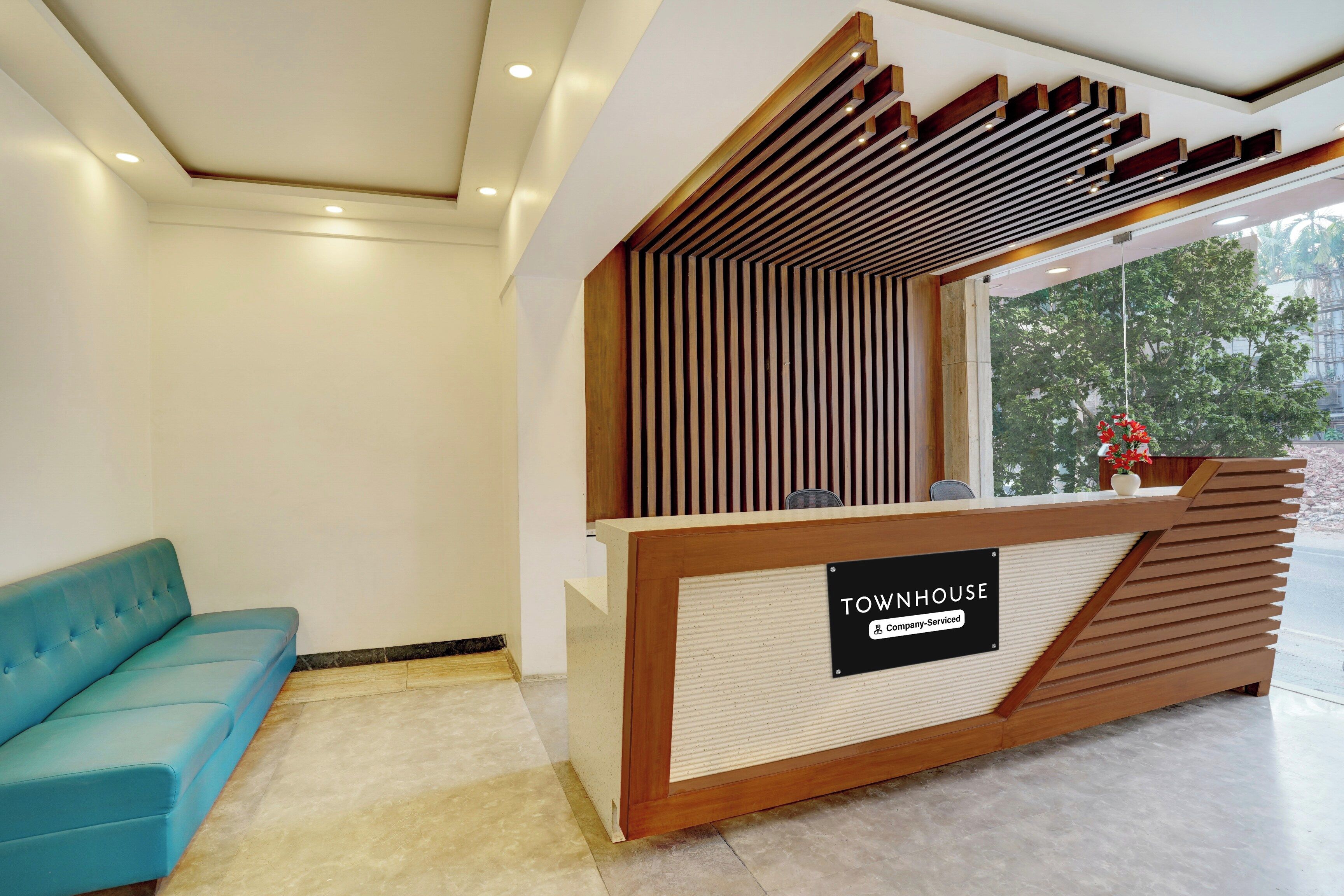 A reception desk with a sign reading 'TOWNHOUSE Company Serviced' and a blue sofa in the background.