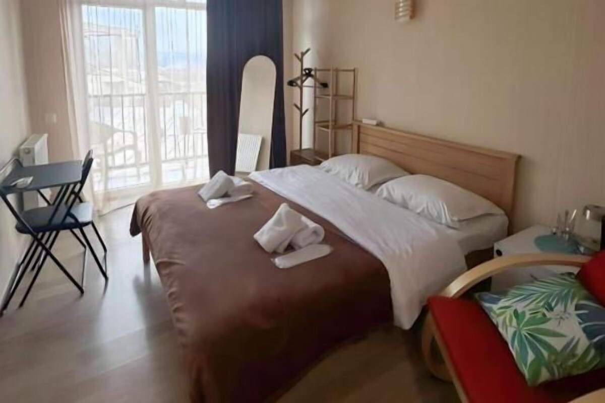 A hotel room with a bed, a desk, and a chair.