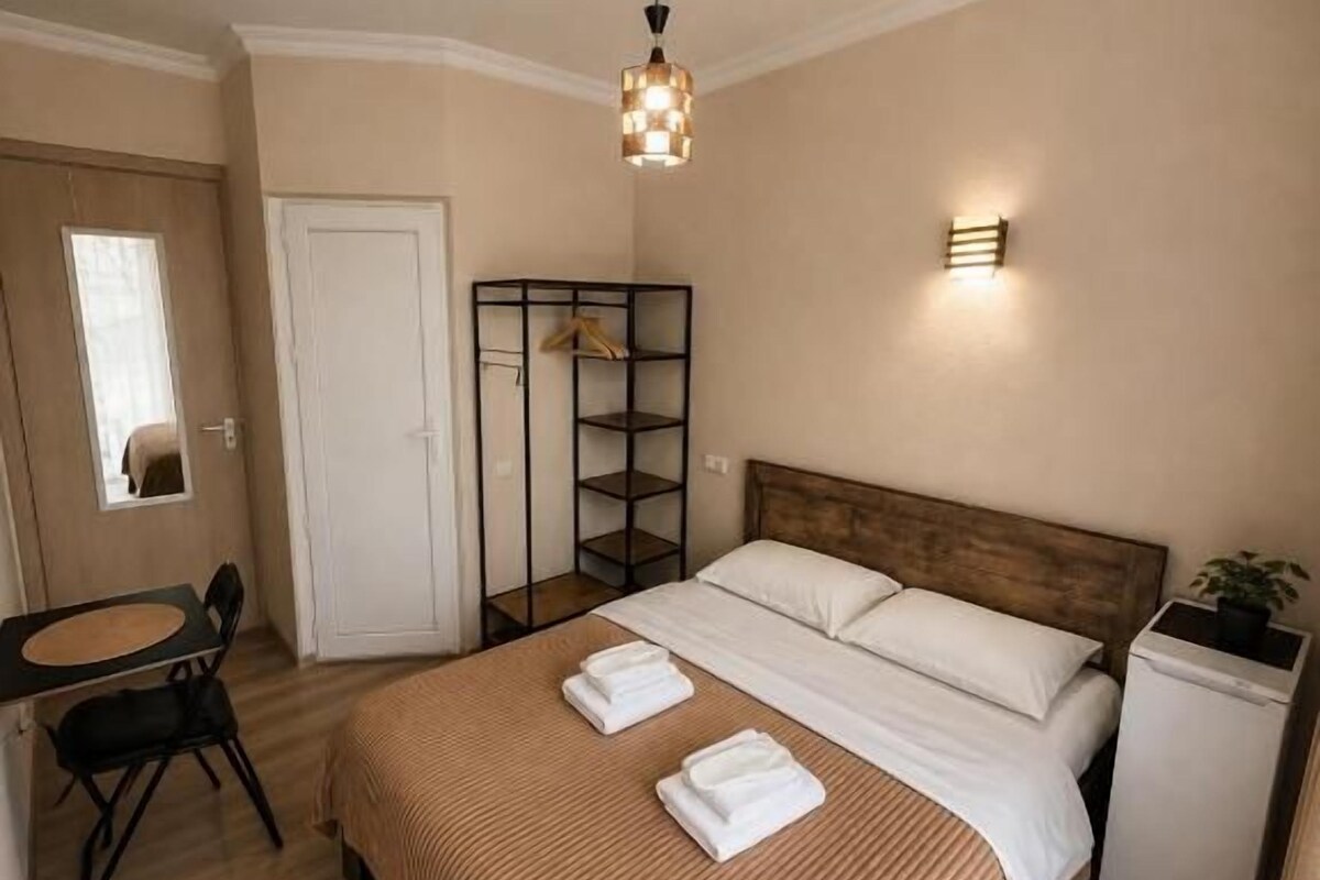 A bedroom with a bed, bedside table, and a hanging light fixture.