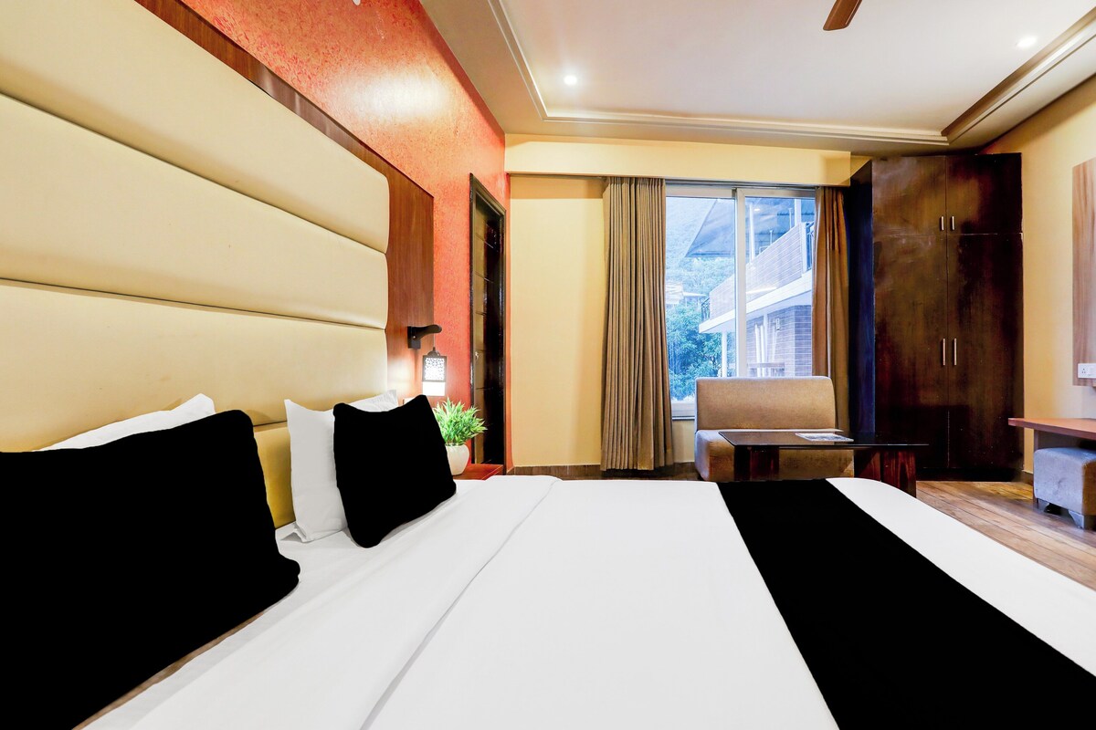 Habitación de hotel con una cama grande, un escritorio, una silla y vistas al exterior.