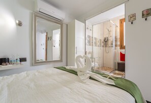 A hotel room with a bed, a large mirror, a shower area, and a small shelf with toiletries. - Bed and Breakfast 'El Duende' with Shared Terrace, Wi-Fi and Air Conditioning (Cómpeta)