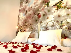 A bed with white linens and rose petals scattered on the surface. - Bed and Breakfast 'El Lucero' with Sea View, Wi-Fi and Air Conditioning (Cómpeta)