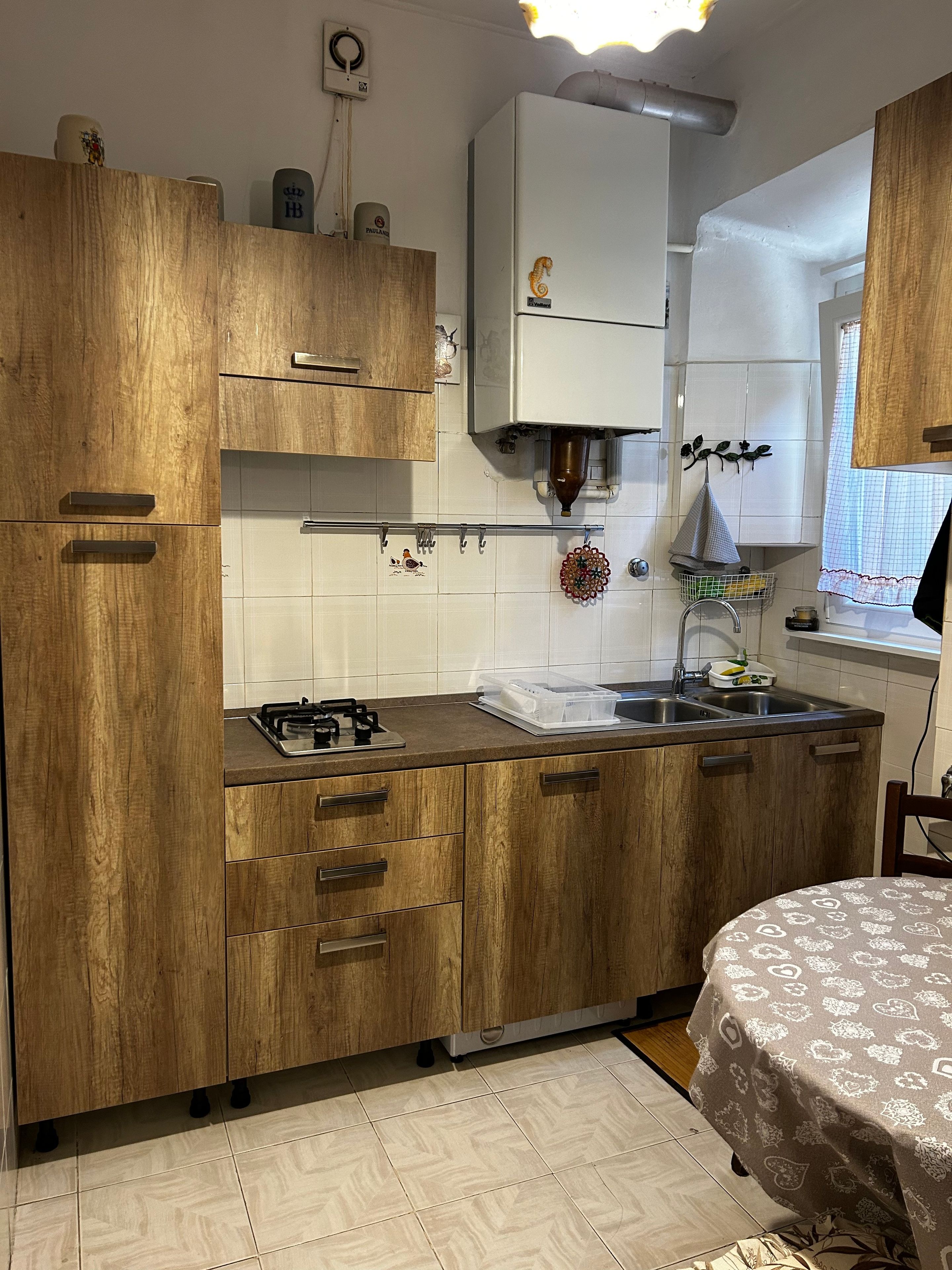 Eine Küche mit Holzausstattung, einem Gasherd, einem Spülbecken und einem Fenster mit Vorhang.