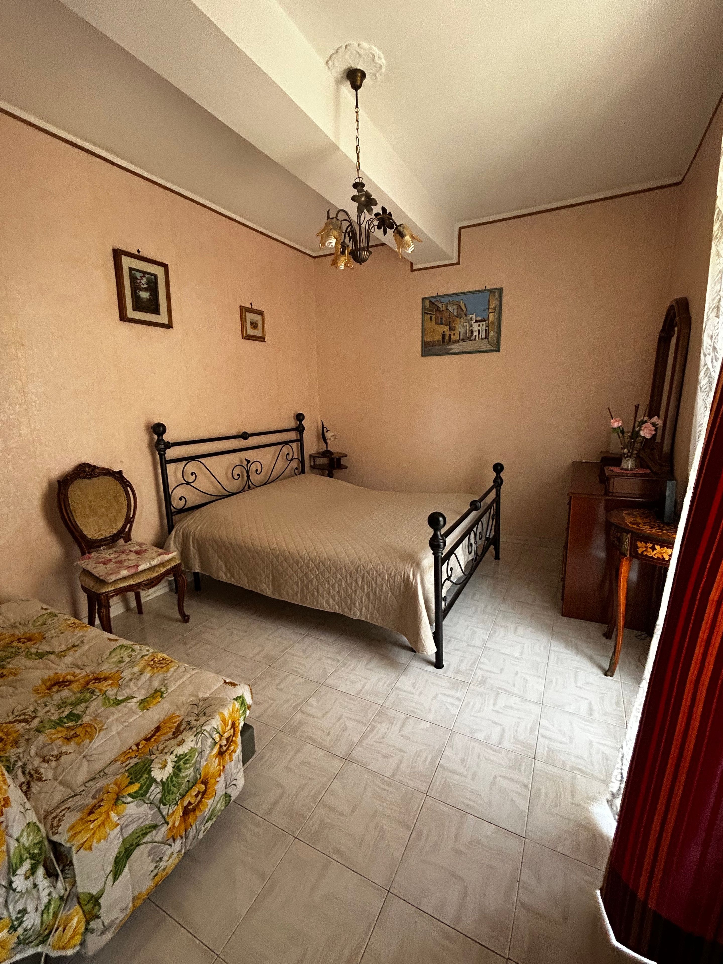 Ein Schlafzimmer mit einem Bett, einem Sessel, einem Schminktisch und einem Deckenventilator.