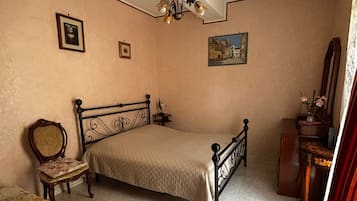 Ein Schlafzimmer mit einem Bett, einem Sessel, einem Schminktisch und einem Deckenventilator.